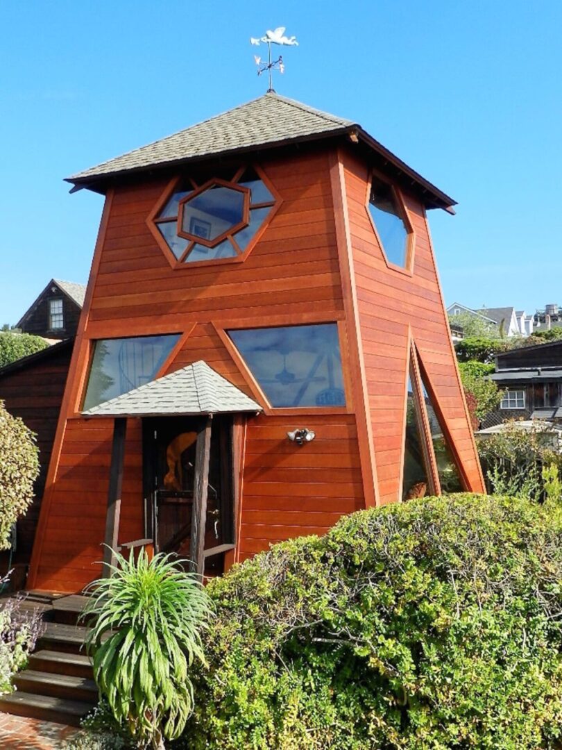 A wooden house with a clock on the front of it.